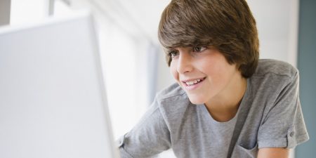 Boy using laptop computer, smiling
