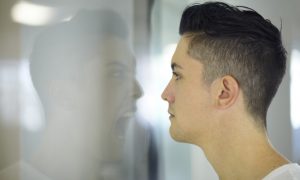 Young man looking at a screaming reflection of himself