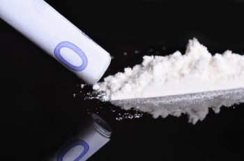 A bank note next to a line of cocaine, ready to be snorted