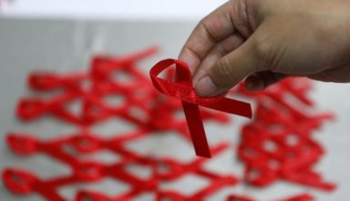 epa05049290 A Taiwanese picks a red ribbon inside the Centers for Disease Control (CDC) building on the eve of World AIDS Day in Taipei, Taiwan, 30 November 2015. World AIDS Day is marked worldwide annually on 01 December to raise awareness for those living with the virus.  EPA/RITCHIE B. TONGO