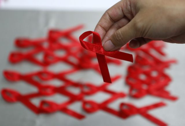 epa05049290 A Taiwanese picks a red ribbon inside the Centers for Disease Control (CDC) building on the eve of World AIDS Day in Taipei, Taiwan, 30 November 2015. World AIDS Day is marked worldwide annually on 01 December to raise awareness for those living with the virus.  EPA/RITCHIE B. TONGO