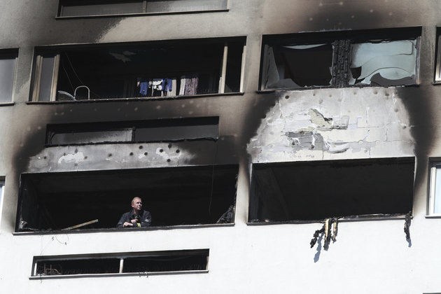 A fireman looks out of a high-rise block after a fire broke-out in a 12th floor flat in Mile End, east London, Friday, June 29, 2018. (Yui Mok/PA via AP)