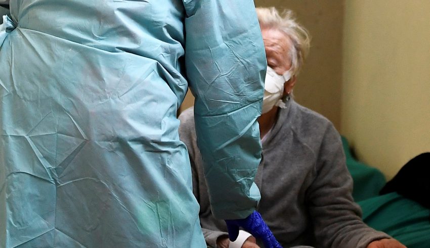 A patient wearing a protective face mask is helped by medical personnel inside the Spedali Civili hospital in Brescia, Italy March 13, 2020. REUTERS/Flavio Lo Scalzo