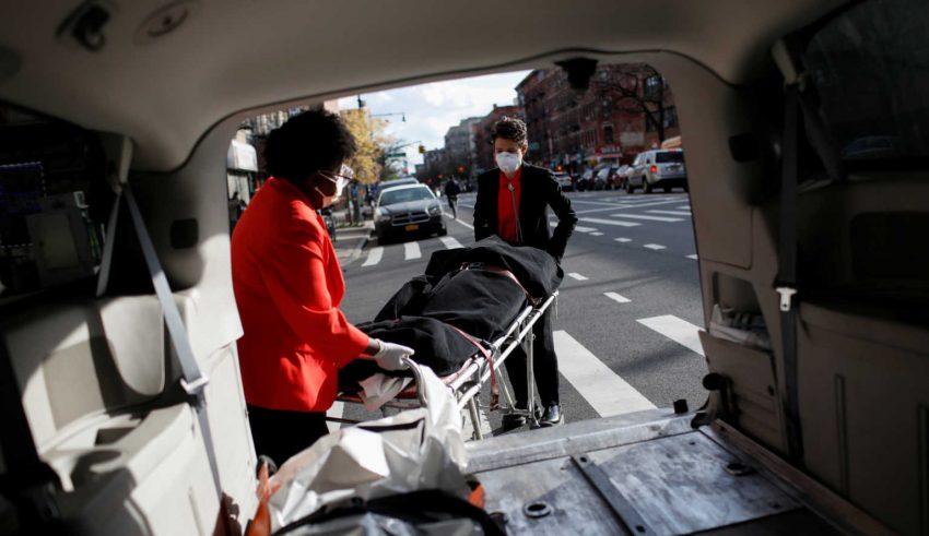 Nicole Warring, 33, and Lily Sage Weinrieb, 25, both of whom are Resident Funeral Directors at International Funeral & Cremation Services, a funeral home in Harlem, remove a deceased person from a funeral service vehicle, during the coronavirus disease (COVID-19) outbreak, in Manhattan, New York City, New York, U.S., April 16, 2020. REUTERS/Andrew Kelly     SEARCH "CORONAVIRUS FUNERAL HOMES SLUM" FOR THIS STORY. SEARCH "WIDER IMAGE" FOR ALL STORIES.
