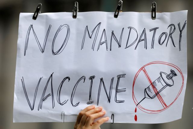 A person holds up a sign during an anti-mandatory coronavirus disease (COVID-19) vaccine protest held outside New York City Hall in Manhattan, New York City, U.S., August 9, 2021. REUTERS/Andrew Kelly