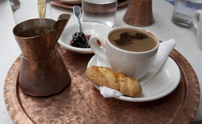 "The coffee, created in 'Briki', served with a cookie, spoon sweets and glass of water. Typical beverage greek and turkish.Taken in Thessaloniki, Greece"