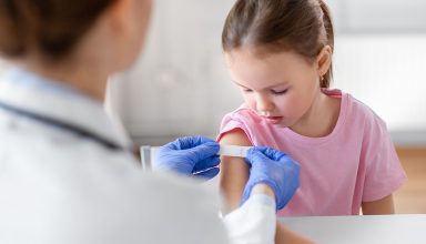 medicine, healthcare and vaccination concept - female doctor or pediatrician talking to little girl patient on medical exam at clinic