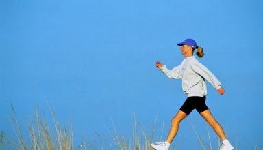Woman speed walking, profile, against blue sky