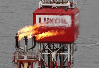 FILE PHOTO: A gas torch is seen next to the Lukoil company sign at the Filanovskogo oil platform in the Caspian Sea, Russia October 16, 2018.  REUTERS/Maxim Shemetov/File Photo