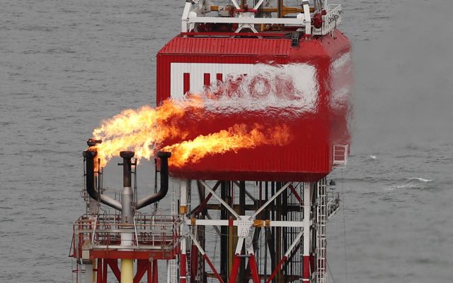 FILE PHOTO: A gas torch is seen next to the Lukoil company sign at the Filanovskogo oil platform in the Caspian Sea, Russia October 16, 2018.  REUTERS/Maxim Shemetov/File Photo