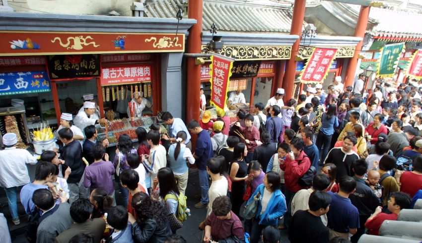 Chinese crowd food stalls in an alley off Wangfujing, Beijing's best-known shopping street, on the fourth day of China's week-long National Day holiday Friday Oct. 4, 2002. The Chinese government has tried to boost its economy by introducing longer holiday breaks in the last few years, in the hope that people will use the time to travel and shop. (AP Photo/Greg Baker)
