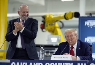 Republican presidential nominee former President Donald Trump arrives for a roundtable, Friday, Oct. 18, 2024, in Auburn Hills, Mich.,as Howard Lutnick, CEO of Cantor Fitzgerald applauds. (AP Photo/Evan Vucci)