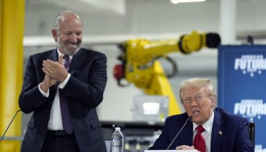 Republican presidential nominee former President Donald Trump arrives for a roundtable, Friday, Oct. 18, 2024, in Auburn Hills, Mich.,as Howard Lutnick, CEO of Cantor Fitzgerald applauds. (AP Photo/Evan Vucci)